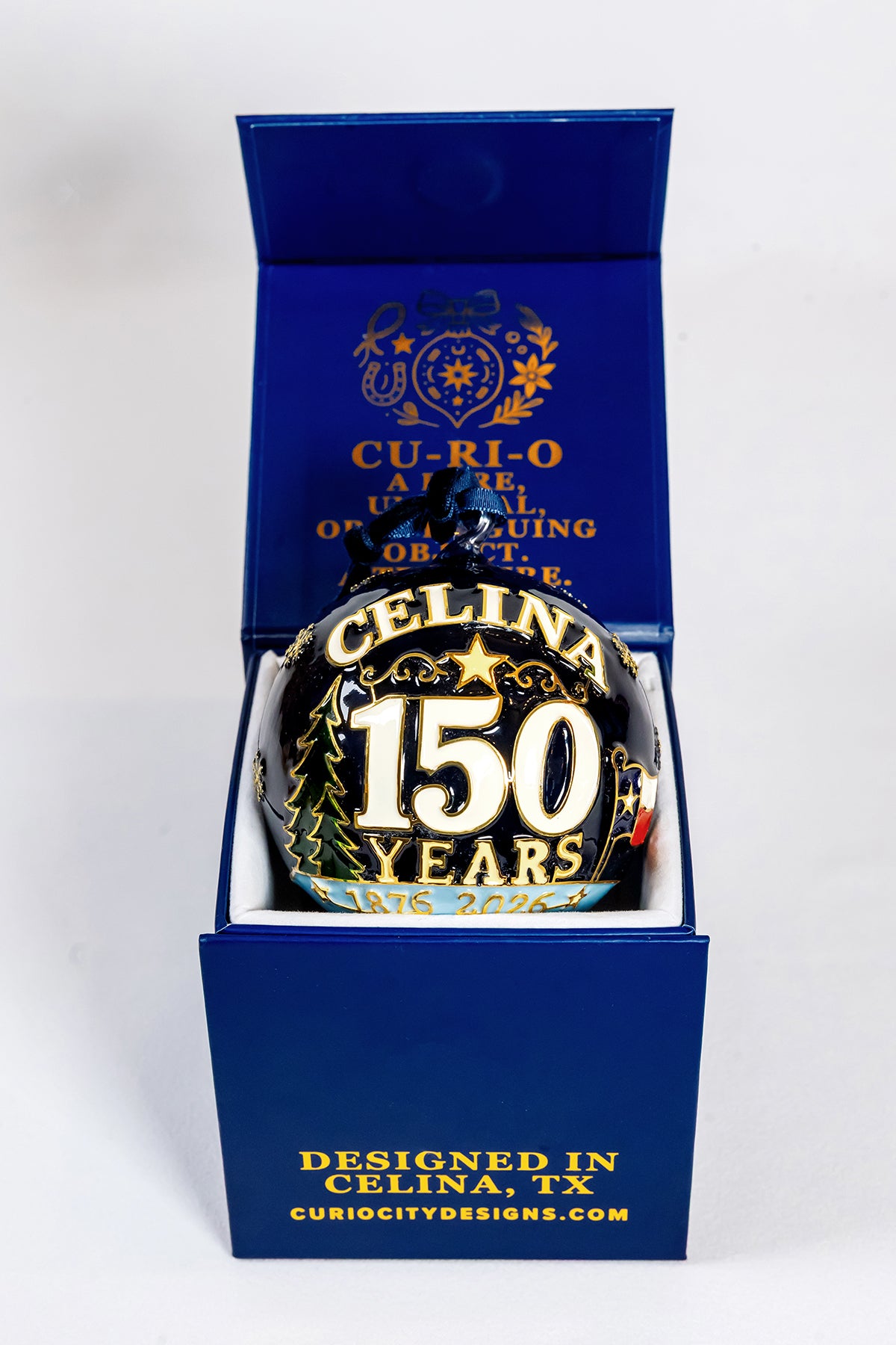 Celina 150 Years 1876 to 2026 hand-painted glass ornament displayed in its CurioCity Designs blue gift box.