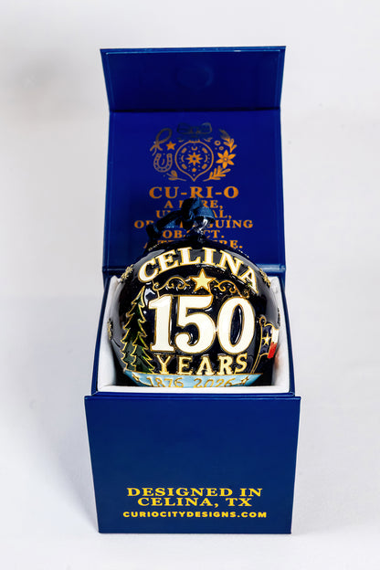 Celina 150 Years 1876 to 2026 hand-painted glass ornament displayed in its CurioCity Designs blue gift box.