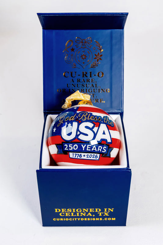 God Bless the USA 250 Years hand-painted glass ornament displayed in an open CurioCity Designs keepsake gift box.