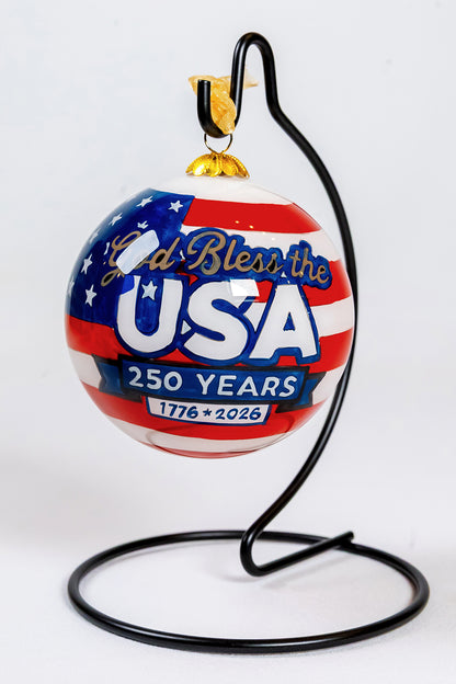 Front view of the God Bless the USA 250 Years glass ornament hanging from a black ornament stand.