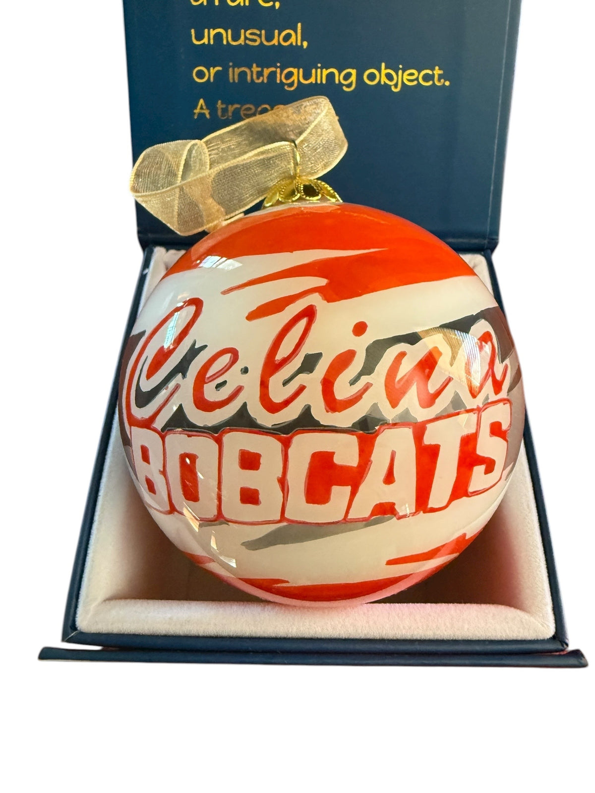 Celina Bobcats Spirit glass ornament with a gold ribbon in an open navy gift box.