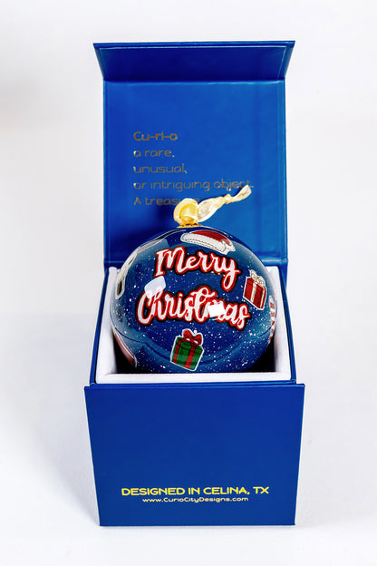 Merry Christmas side of Prosper Texas hand-painted glass ornament in CurioCity Designs blue gift box