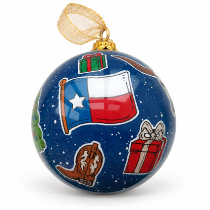 Texas-flag side of A Celina Christmas glass ornament, showing a cowboy boot and wrapped gifts on a navy snowy background, styled with gold ribbon.