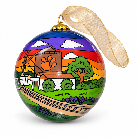 Historical Downtown Celina glass ornament styled with a gold ribbon, showing the water tower, train tracks, and colorful sunset.